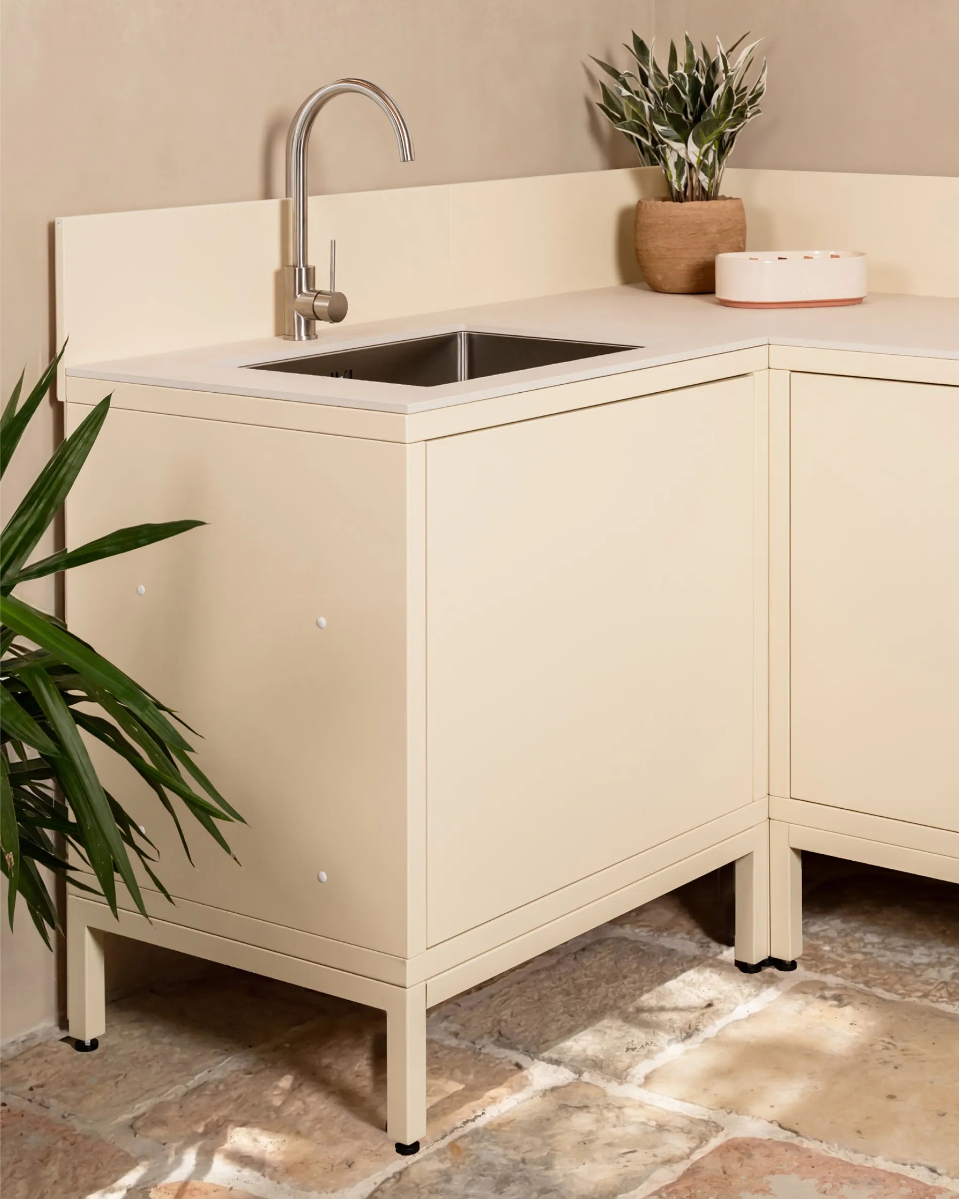 Structure basse beige crème PILOTIS sous caisson d'angle évier, cuisine extérieure avec robinet et plante