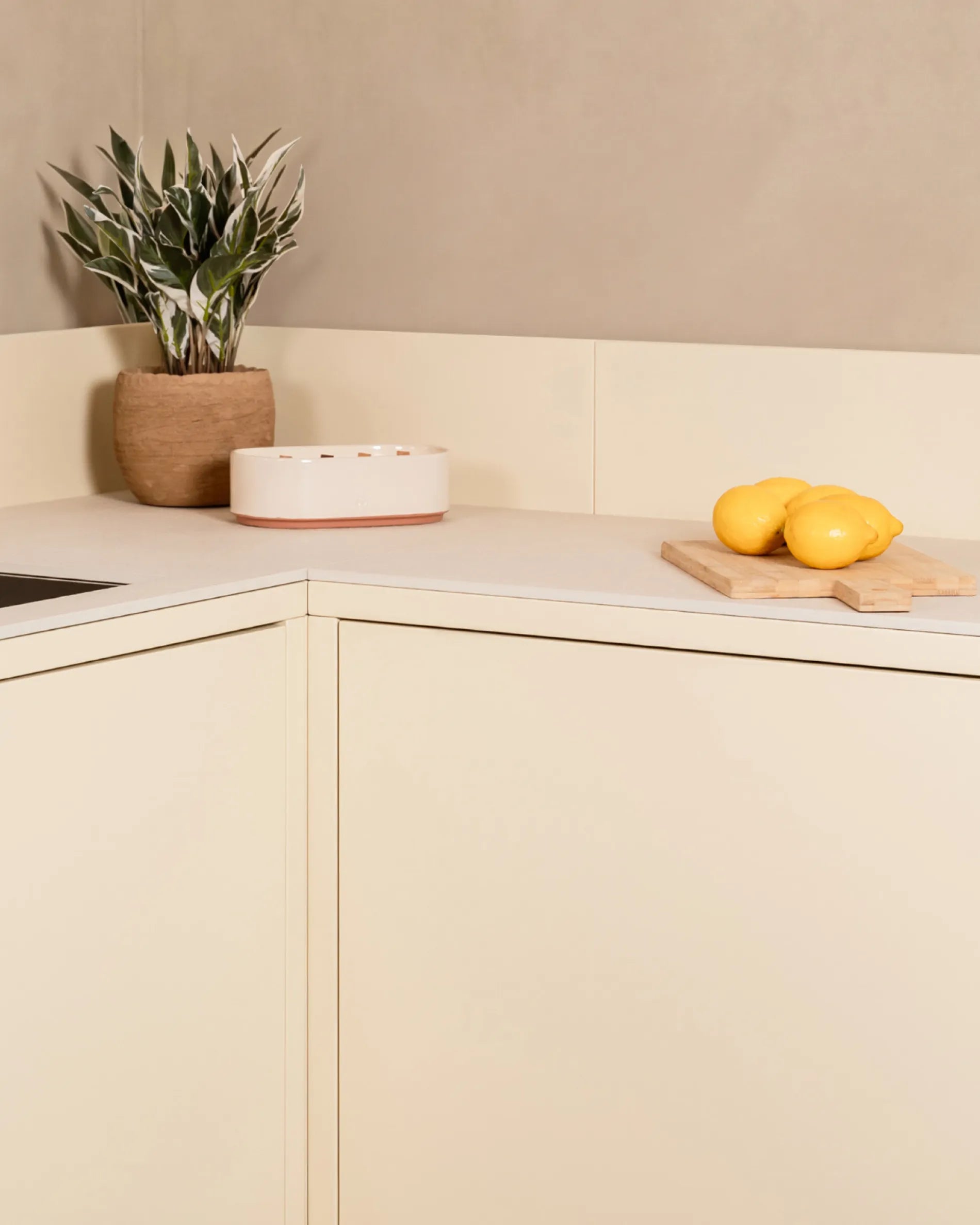 Caisson d'angle beige crème PILOTIS en cuisine extérieure, avec plante et citrons sur planche