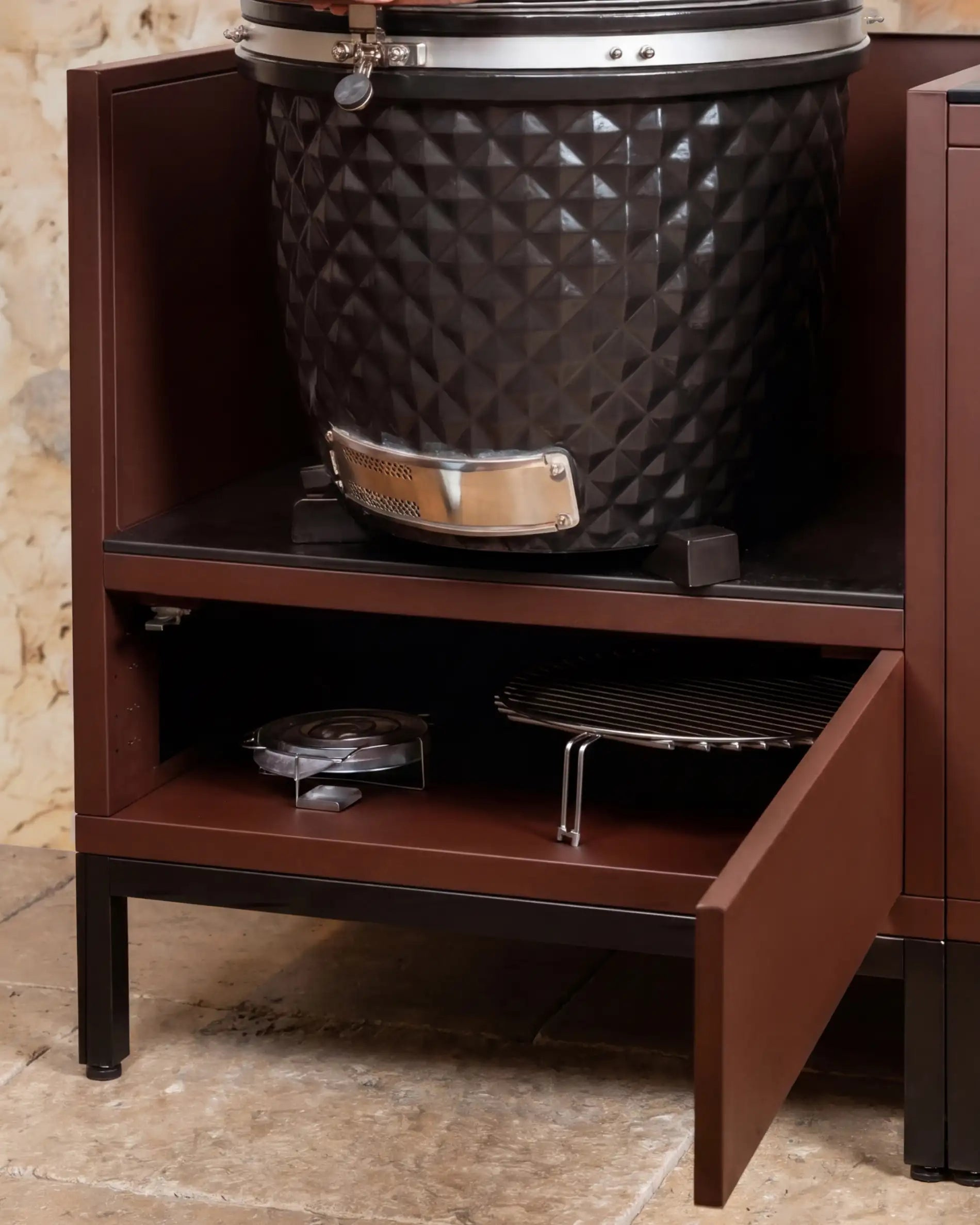 Kamado Kokko noir intégré dans un module rust avec étagère de rangement ouverte et accessoires de cuisson