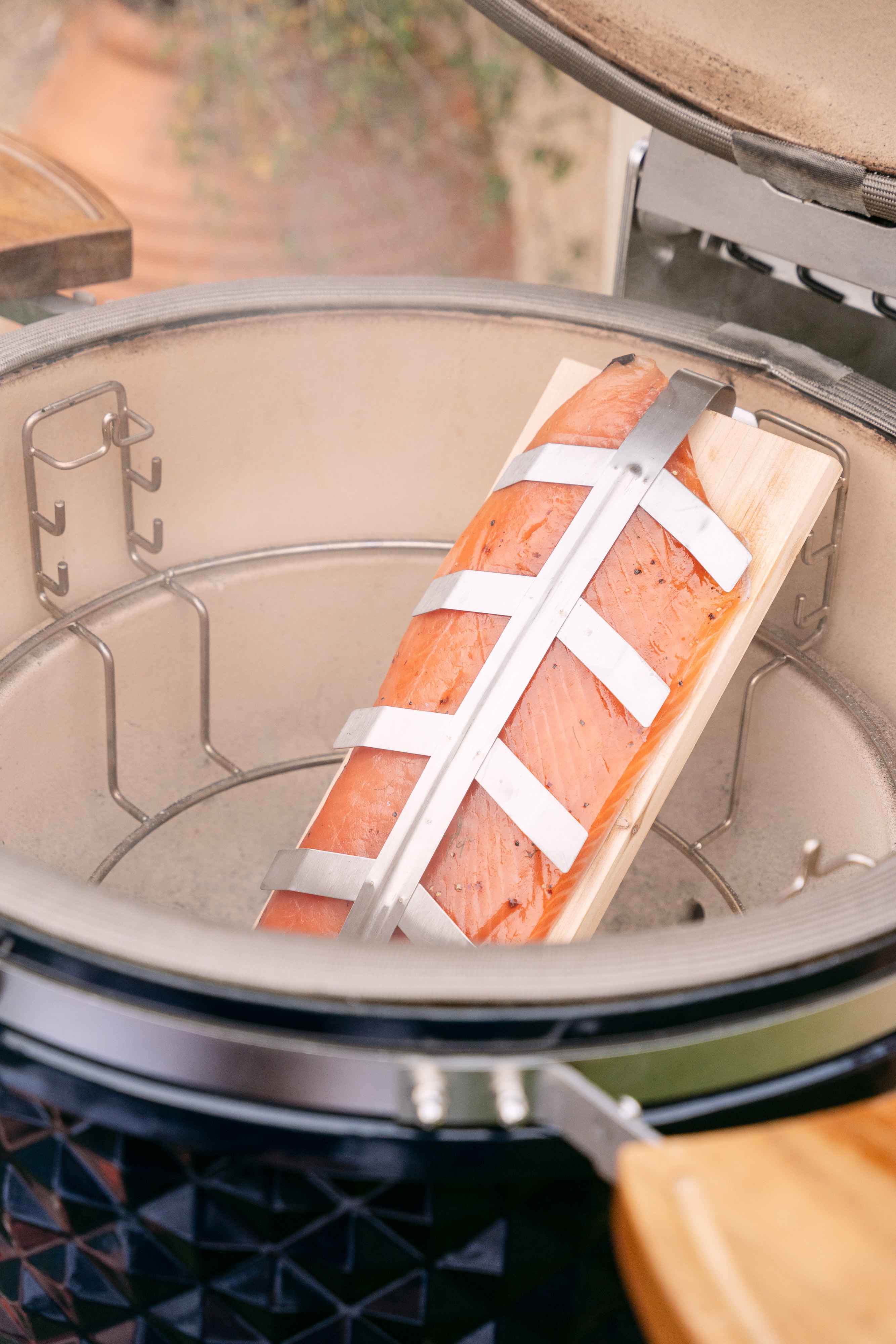 Filete de salmón ahumado sobre una tabla de madera en un kamado de cerámica Kokko